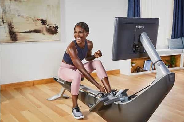 Hydrow athlete smiling whilst sitting on rower